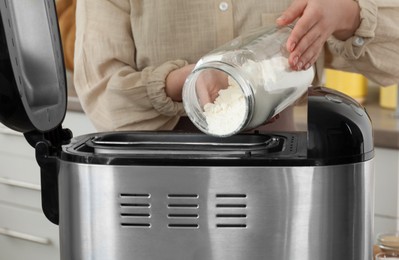 Photo of Making dough. Woman adding flour into breadmaker machine, closeup