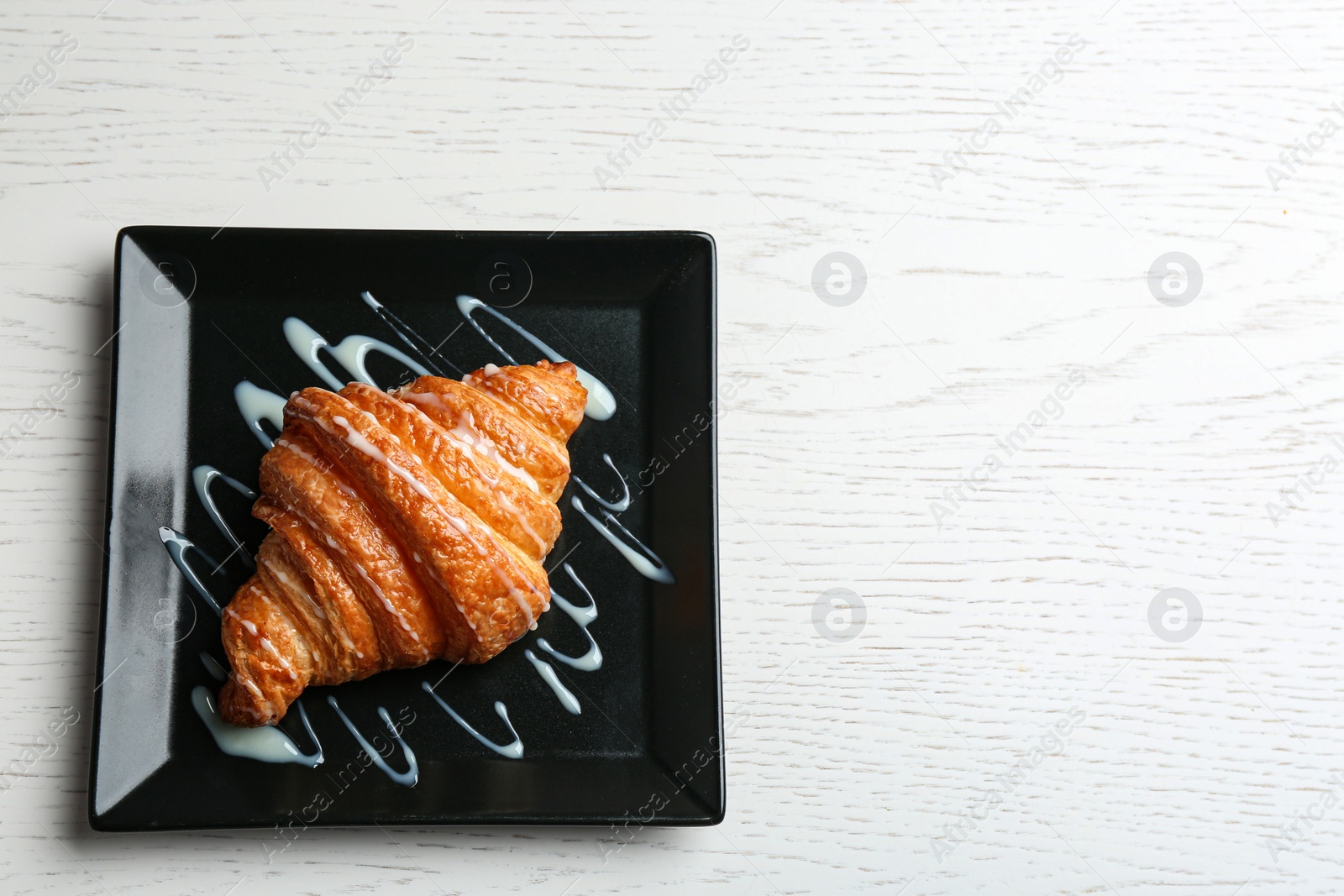 Photo of Plate of tasty croissant with sauce and space for text on white wooden background, top view. French pastry