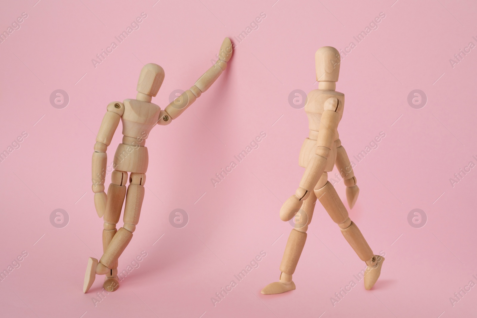 Image of Wooden human models in different poses on pink background