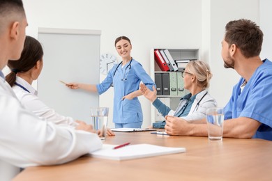 Doctor giving lecture near flipchart in conference room