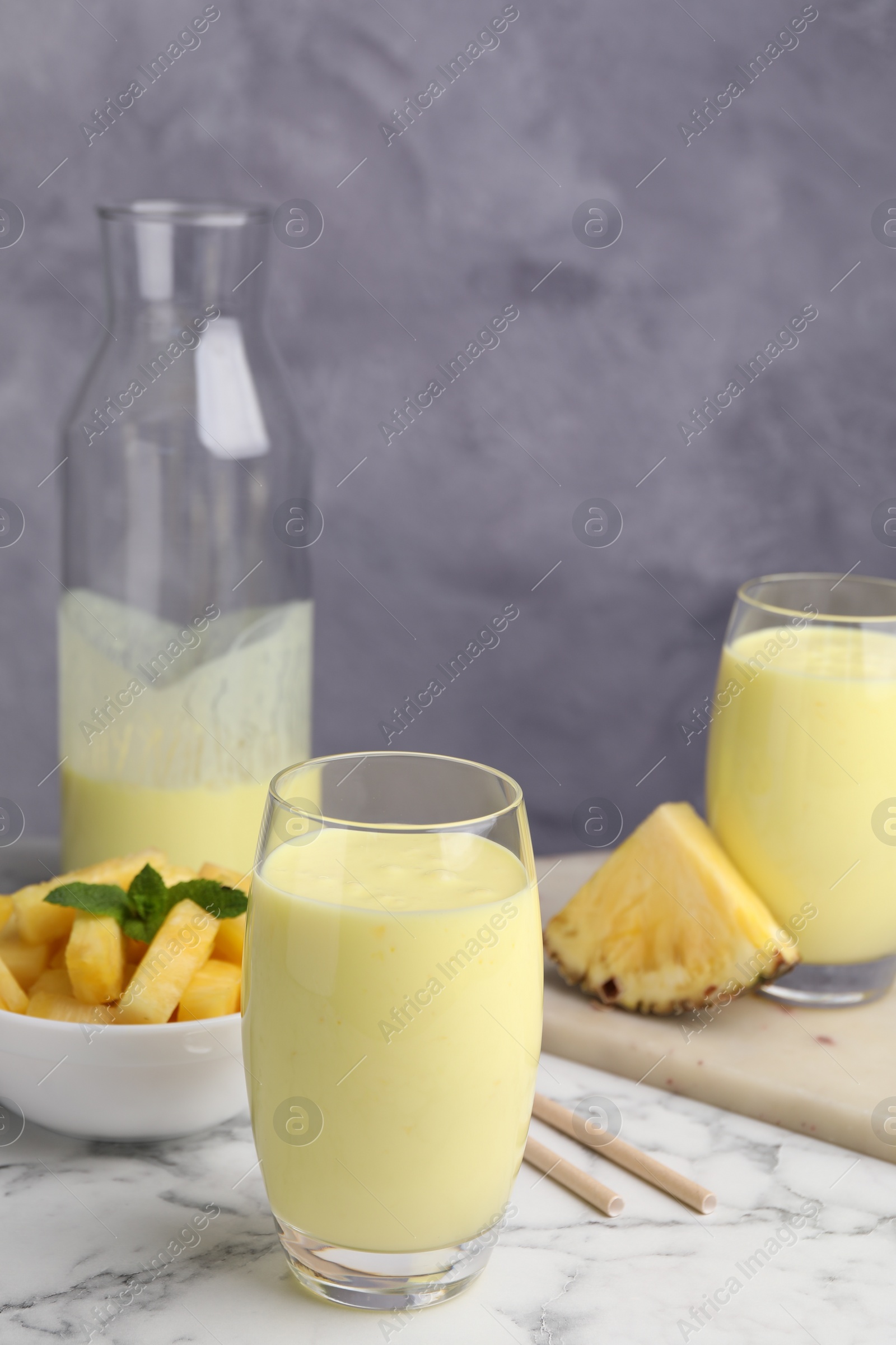 Photo of Tasty pineapple smoothie on white marble table, space for text
