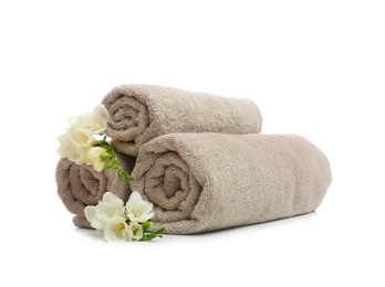 Photo of Clean rolled towels with flowers on white background