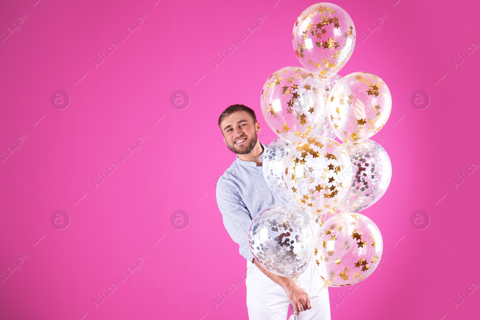 Photo of Young man with air balloons and space for text on color background