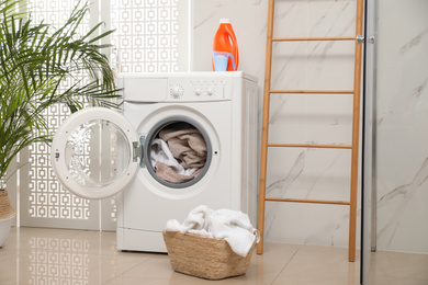 Modern washing machine with towels in bathroom