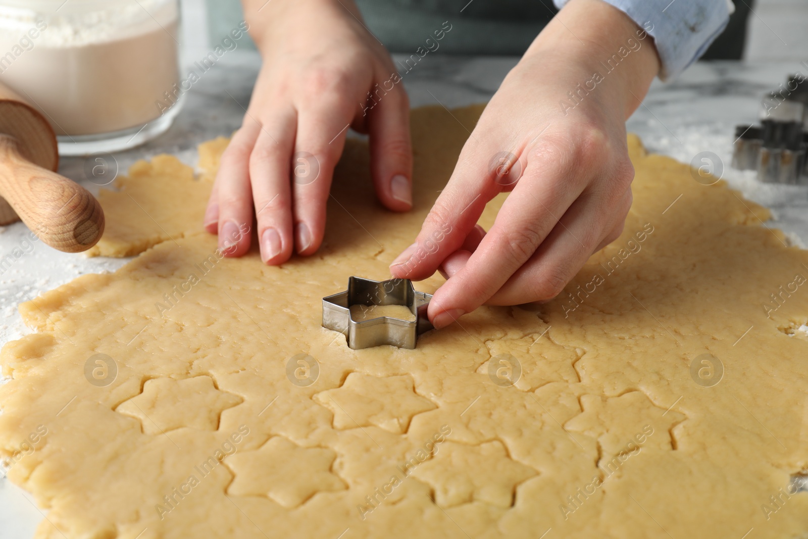 Photo of Shortcrust pastry. Woman making cookies with cutter at table, closeup