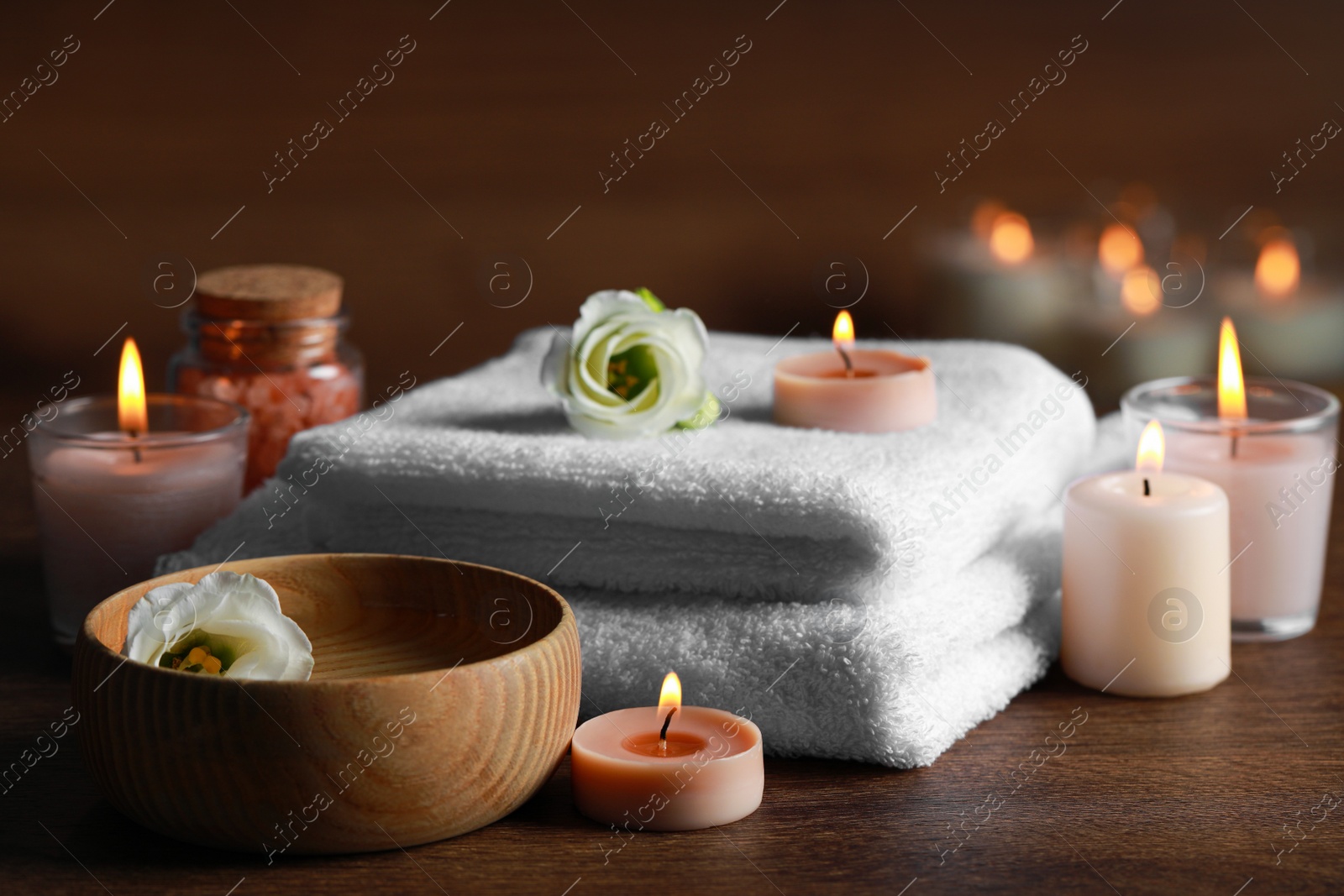 Photo of Beautiful spa composition with burning candles and flowers on wooden table