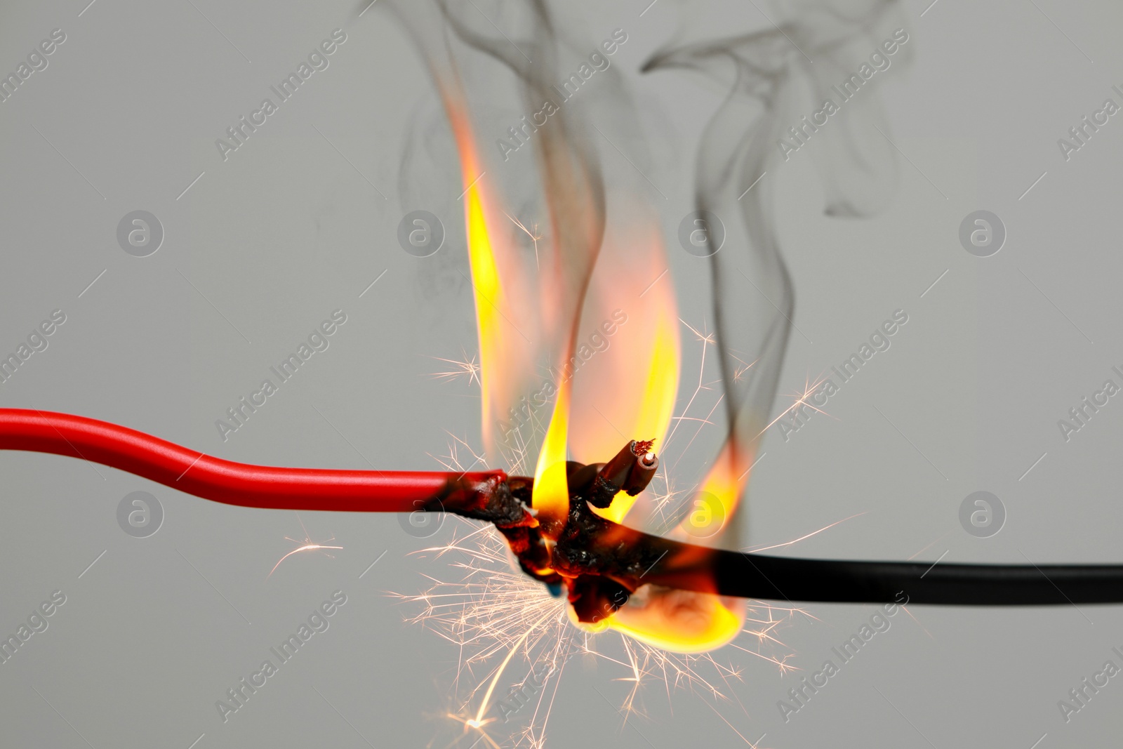 Image of Electrical wire burning and sparking on light background, closeup