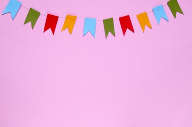 Photo of Colorful bunting flags on pink background, flat lay. Space for text