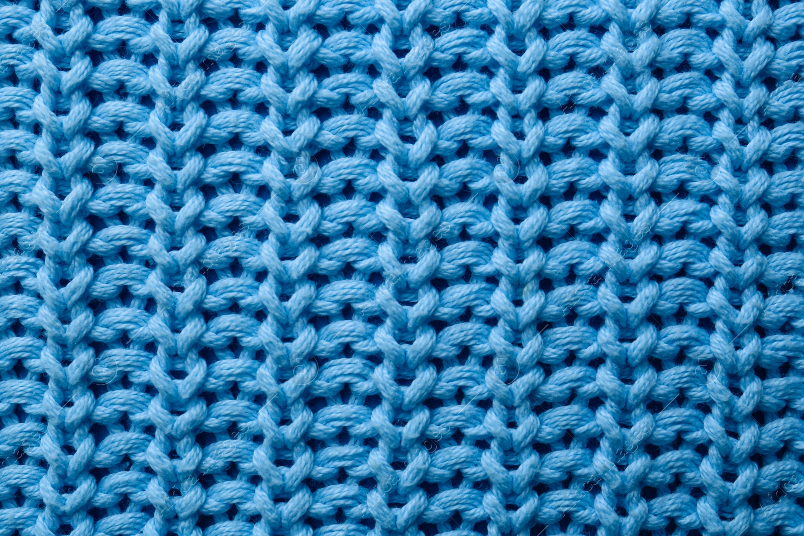 Photo of Beautiful light blue knitted fabric as background, top view