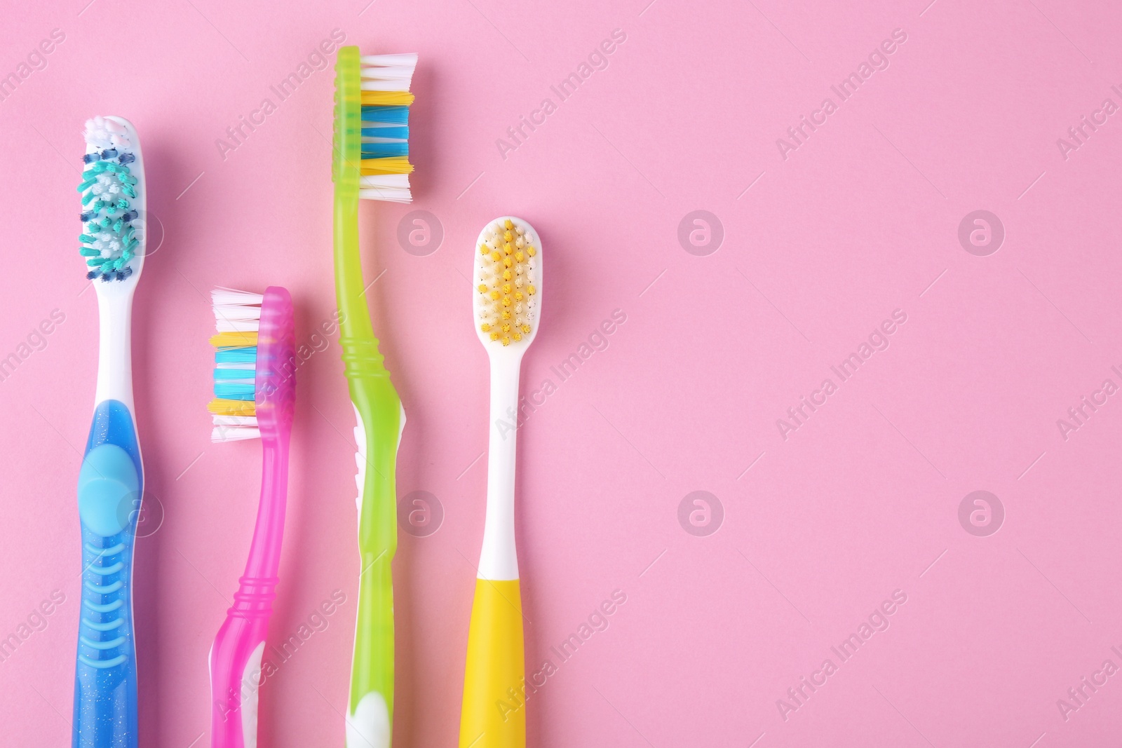 Photo of Many different toothbrushes on pink background, flat lay. Space for text