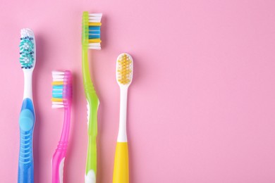 Many different toothbrushes on pink background, flat lay. Space for text