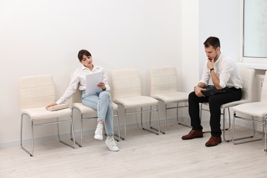 Man and woman waiting for job interview indoors
