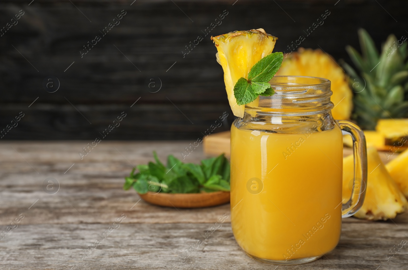 Photo of Mason jar with delicious pineapple juice on table