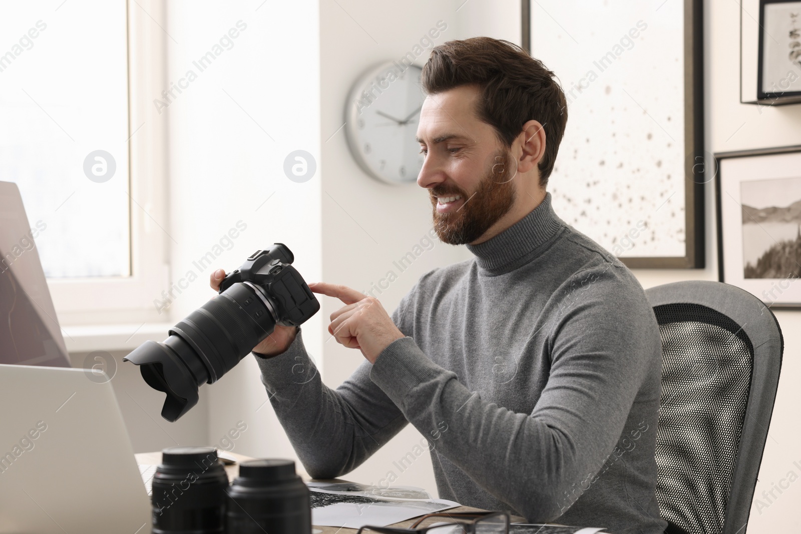 Photo of Professional photographer with digital camera at table in office