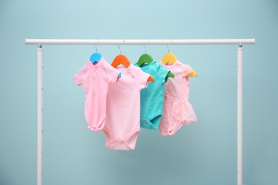 Baby clothes hanging on rack against color background