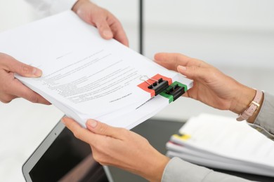 Photo of Woman giving documents to colleague in office, closeup