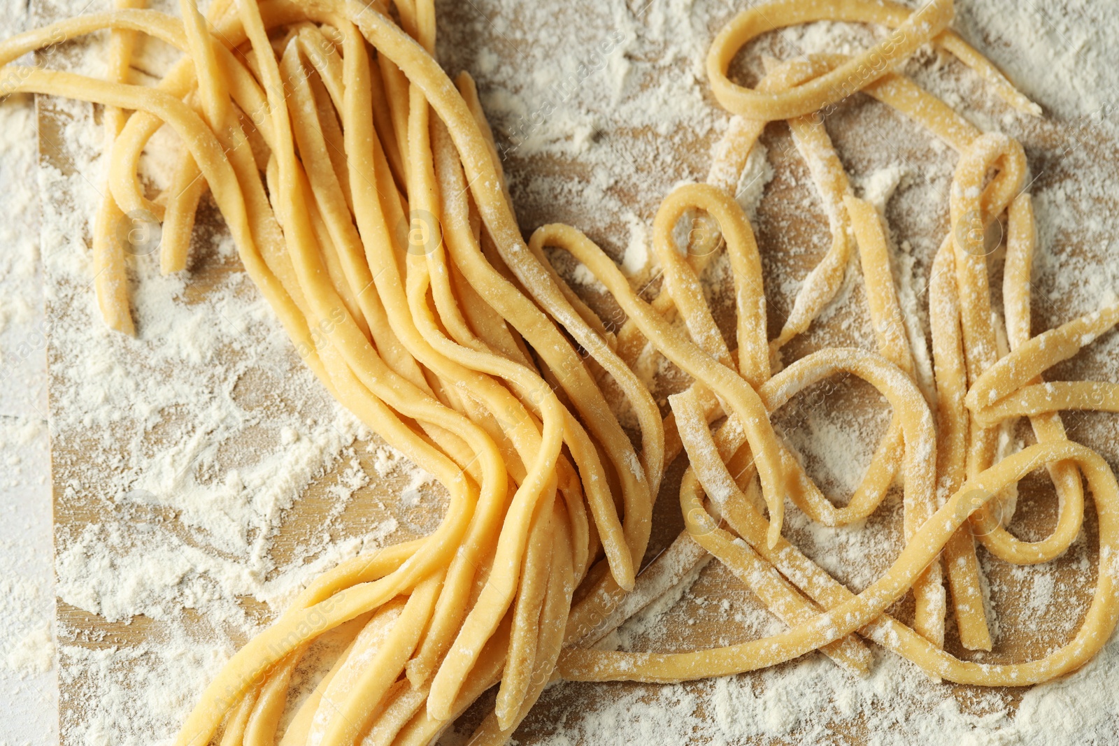 Photo of Raw homemade pasta and flour on wooden board