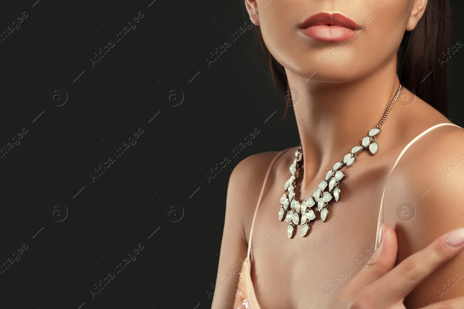 Photo of Beautiful young woman with elegant jewelry on dark background, closeup. Space for text