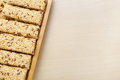 Plate with tasty sesame seed bars on wooden table, top view. Space for text