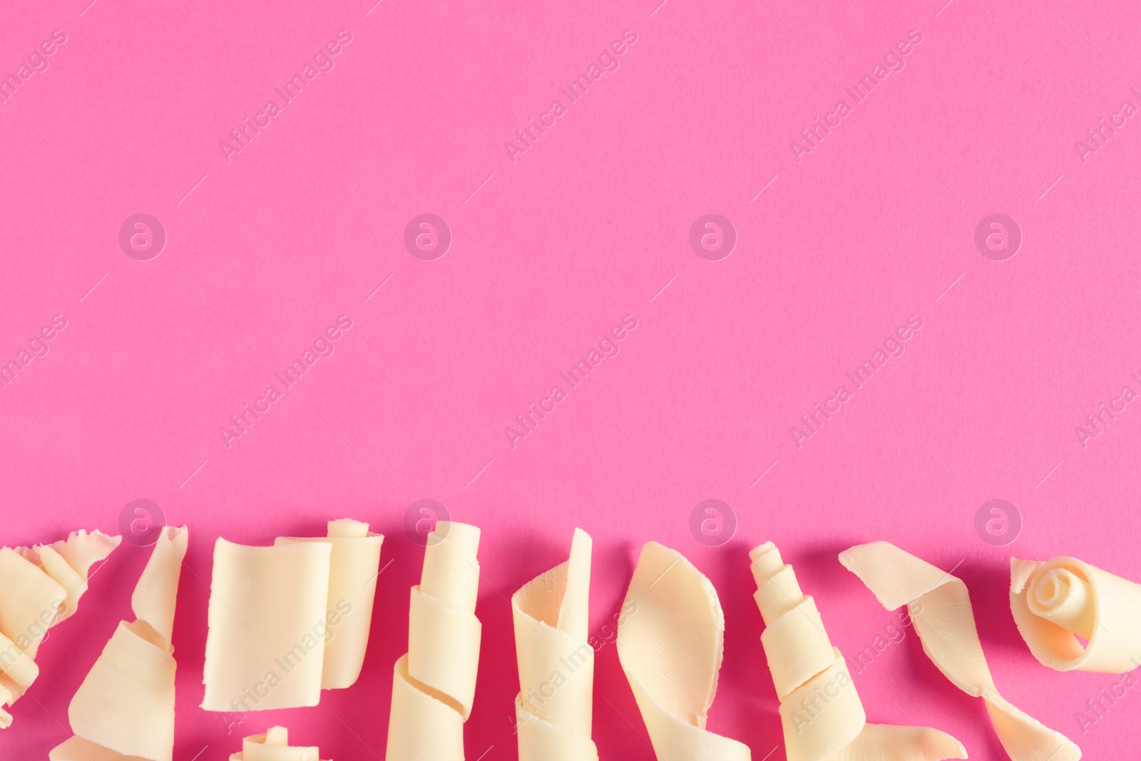 Photo of Yummy white chocolate curls and space for text on color background, top view