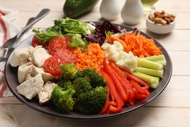 Photo of Balanced diet and healthy foods. Plate with different delicious products on light wooden table, closeup