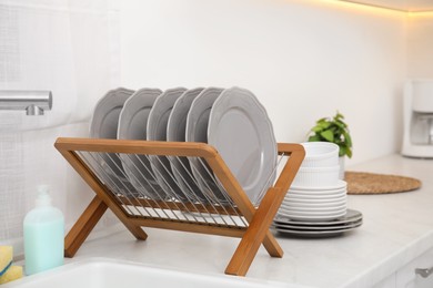Photo of Clean dishes on wooden drying rack in stylish kitchen