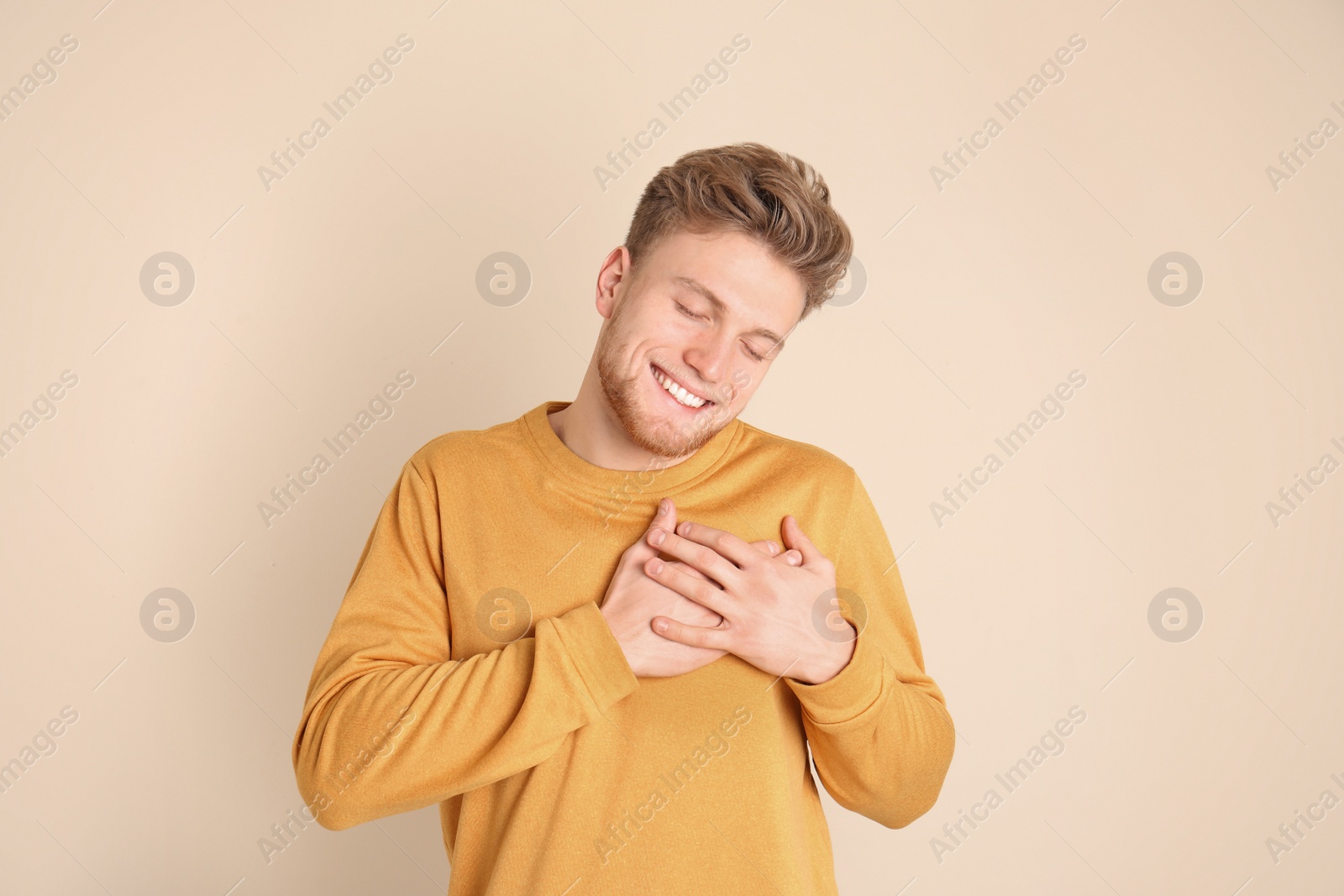 Photo of Portrait of young man holding hands near heart on color background