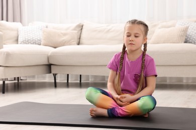 Photo of Little girl meditating at home, space for text. Harmony and zen