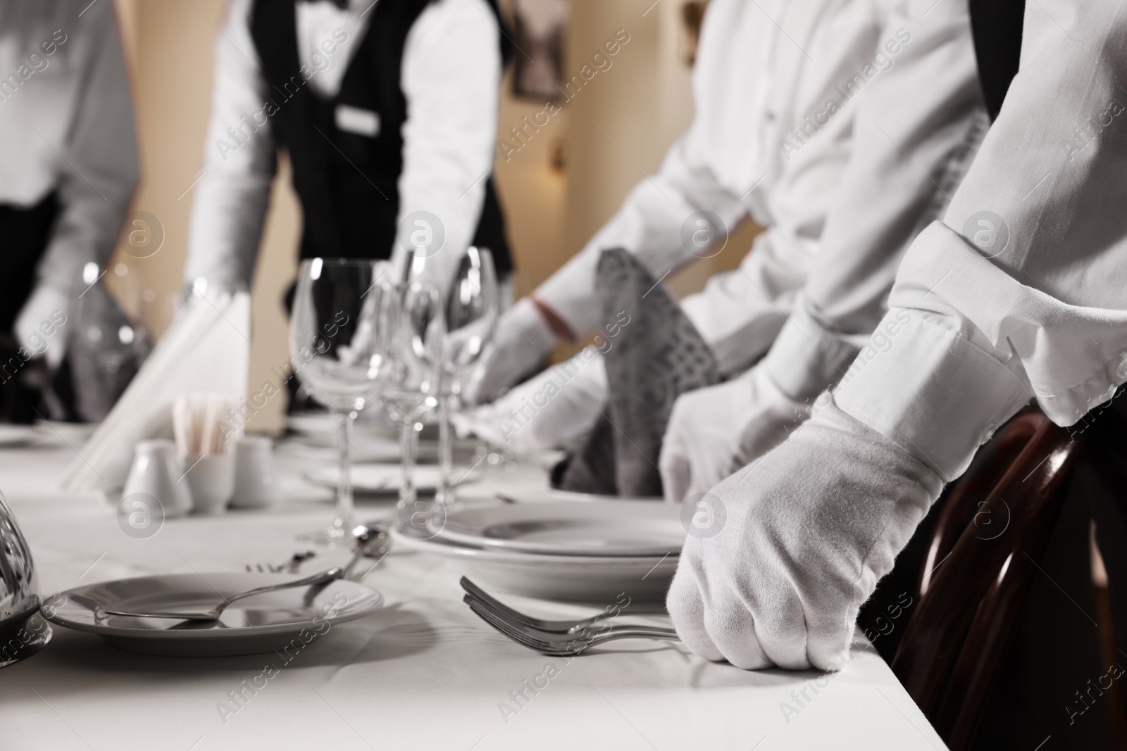 Photo of People setting table during professional butler courses in restaurant, closeup