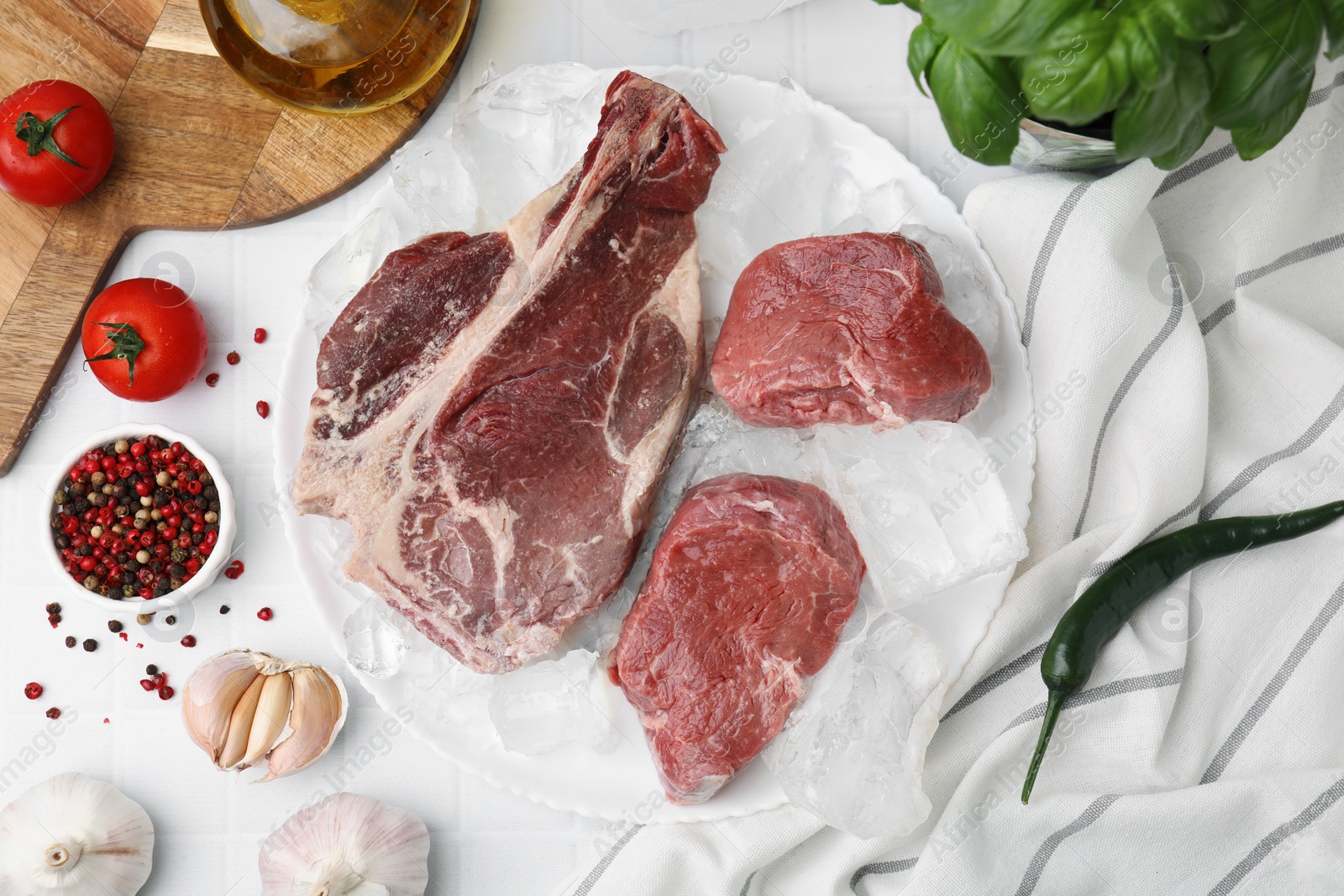 Photo of Flat lay composition with cut fresh beef meat on white tiled table