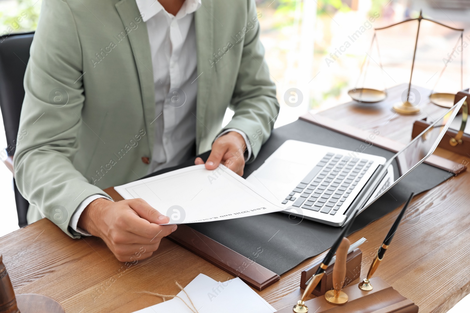 Photo of Male notary with documents and laptop at table in office, closeup