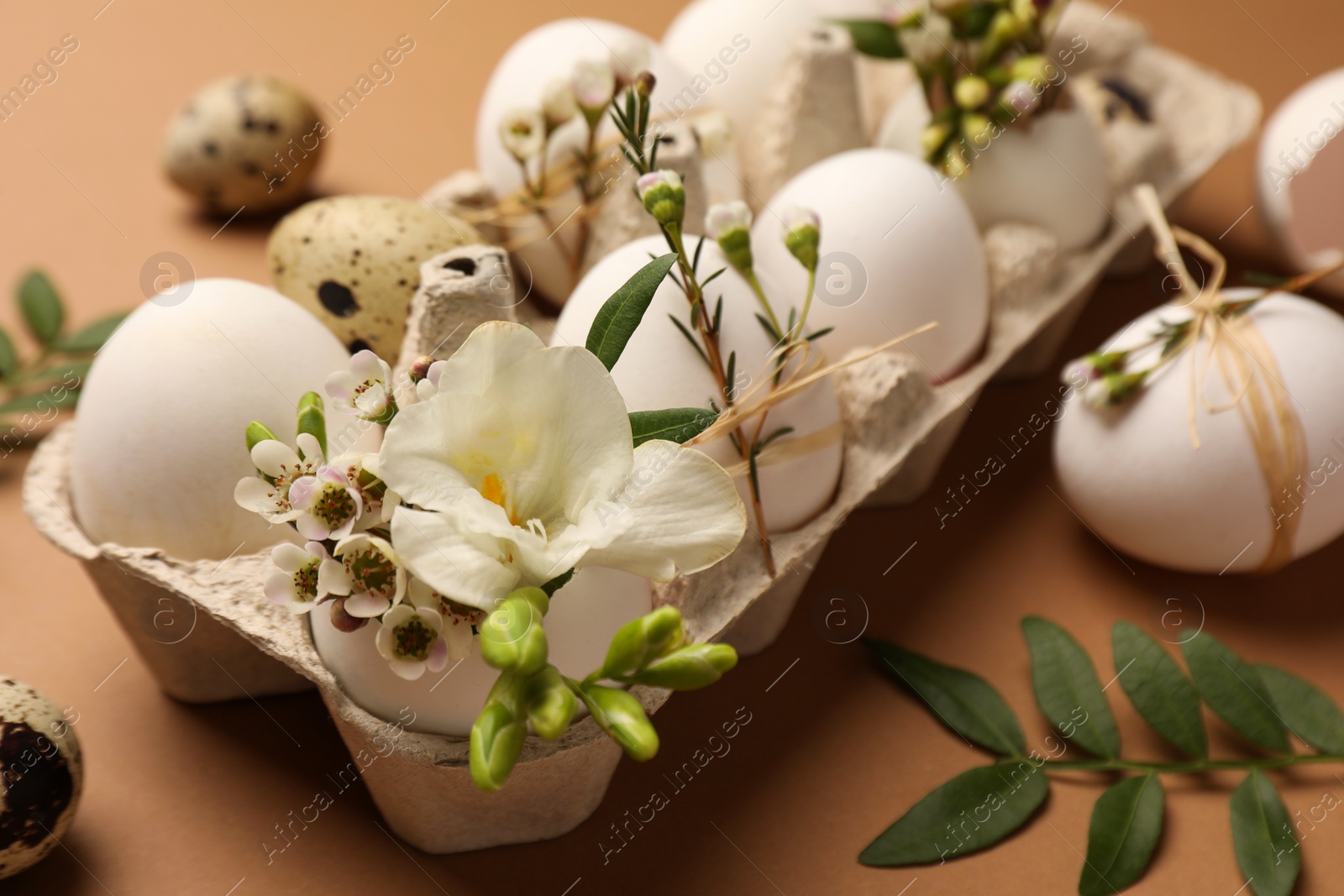 Photo of Festive composition with eggs and floral decor on brown background, closeup. Happy Easter