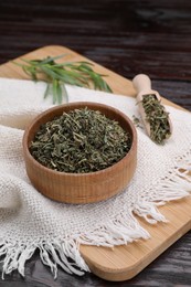 Dry tarragon in bowl on wooden table