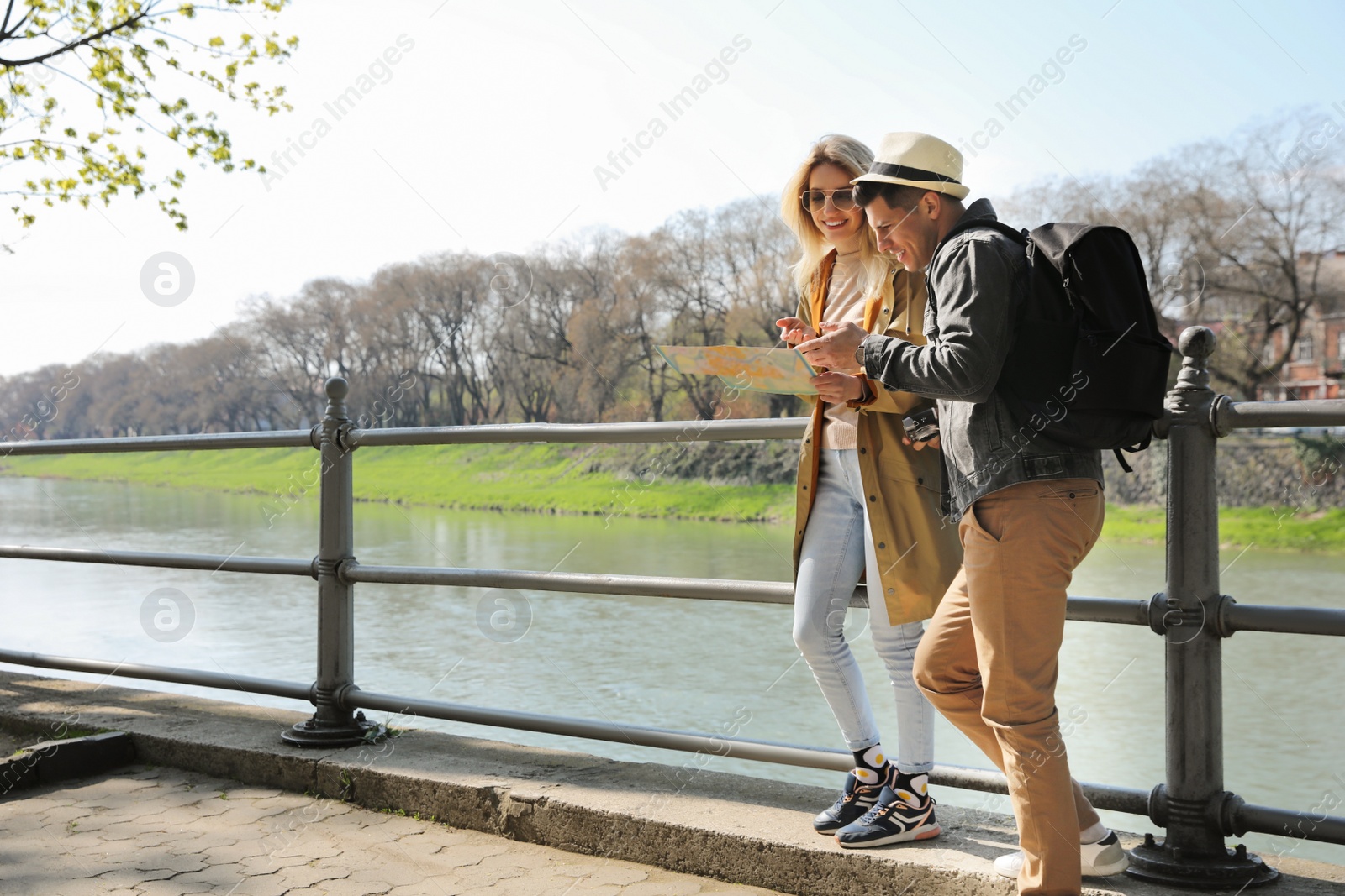 Photo of Couple of tourists with map on city street near beautiful river