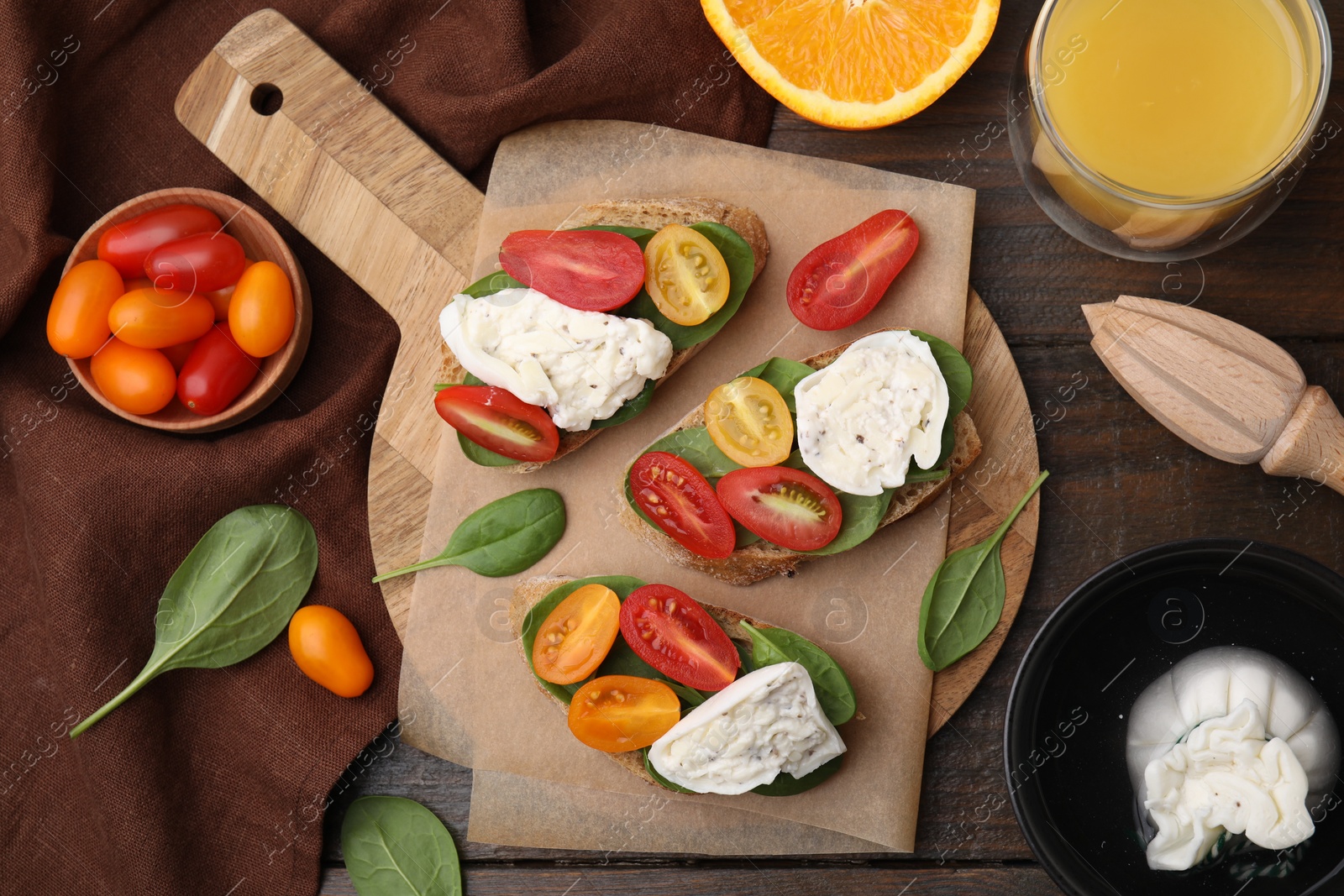 Photo of Delicious sandwiches with burrata cheese and tomatoes served on wooden table, flat lay