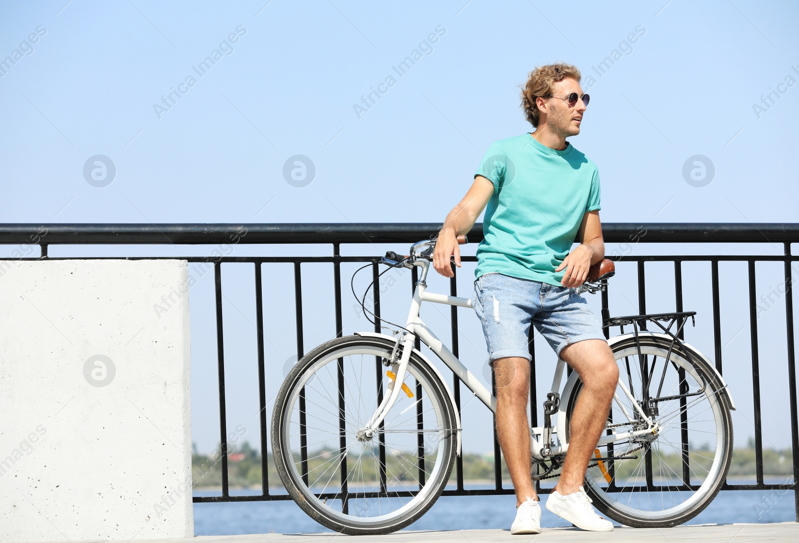 Photo of Handsome young man with bicycle outdoors on sunny day