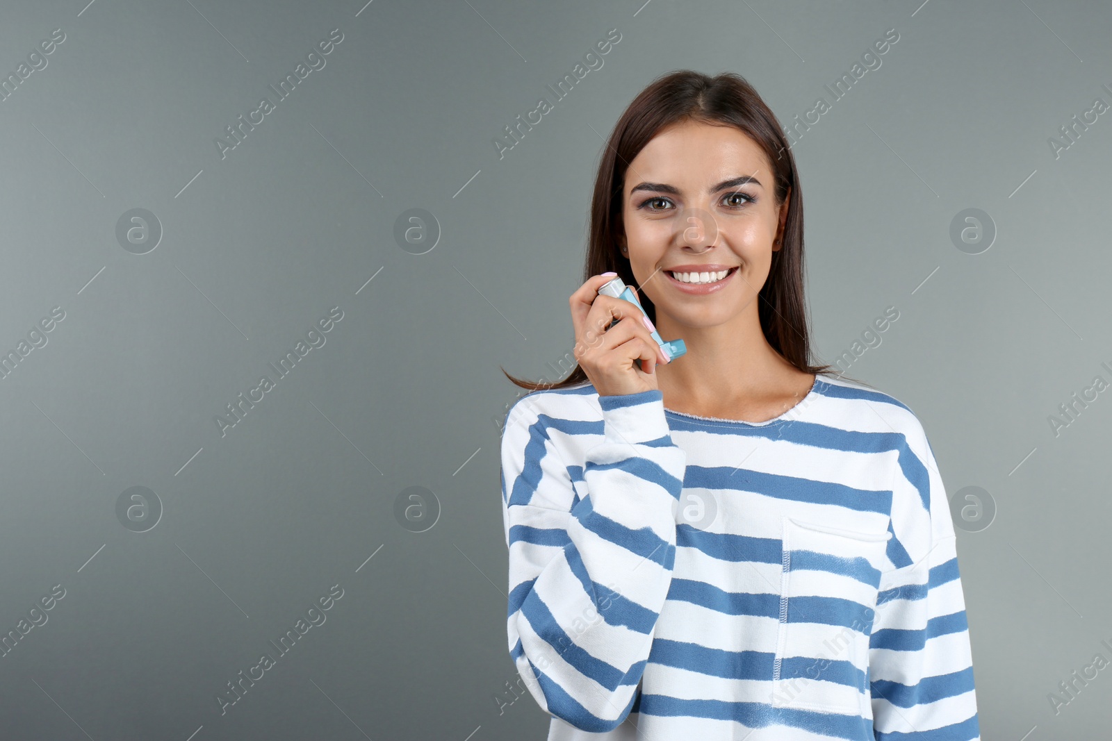 Photo of Young woman with asthma inhaler and space for text on color background