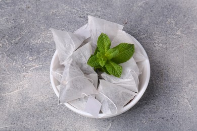 Photo of Tea bags and mint on light grey table, above view