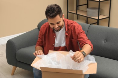 Photo of Man unpacking parcel at home. Online shopping