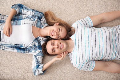 Photo of Lovely young couple lying on cozy carpet at home