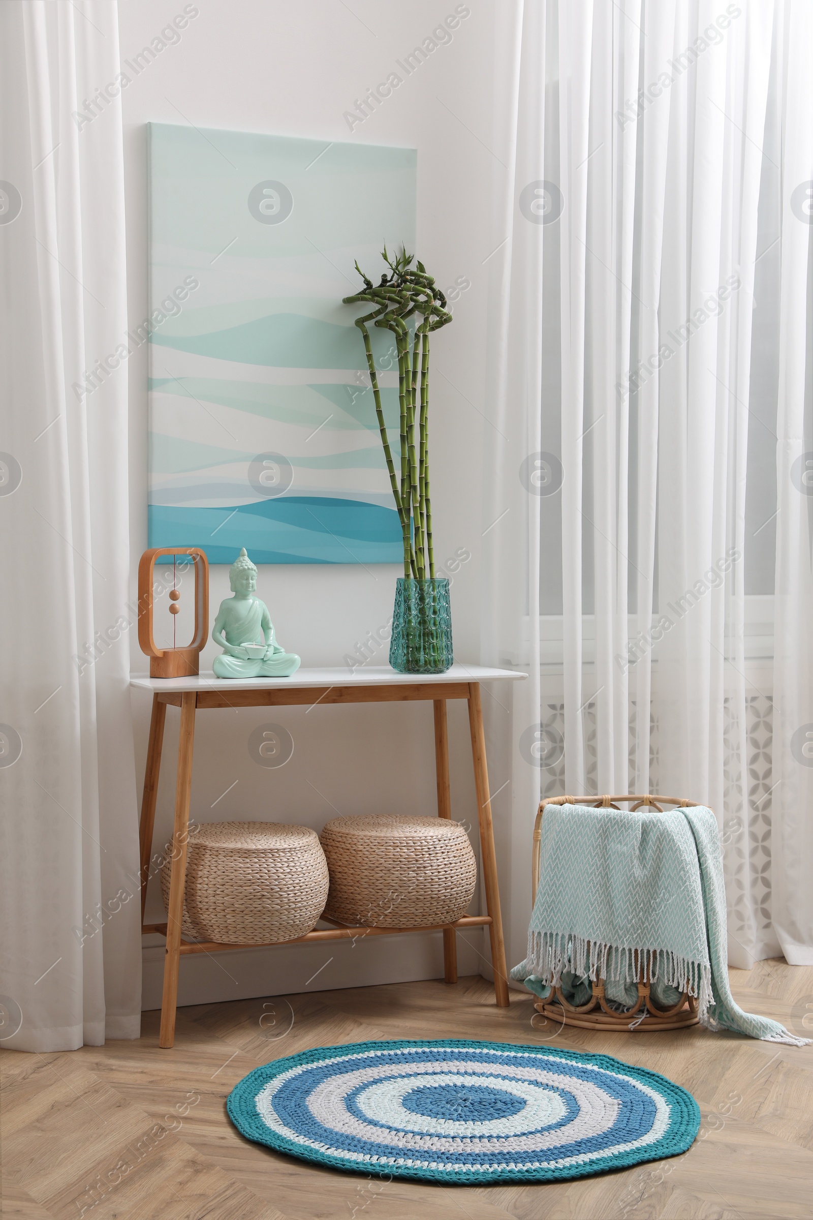 Photo of Console table with bamboo and Buddha statue near light wall indoors. Interior design