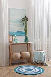 Photo of Console table with bamboo and Buddha statue near light wall indoors. Interior design