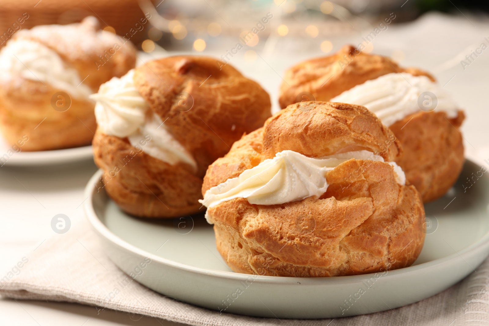 Photo of Delicious profiteroles with cream filling on table, closeup