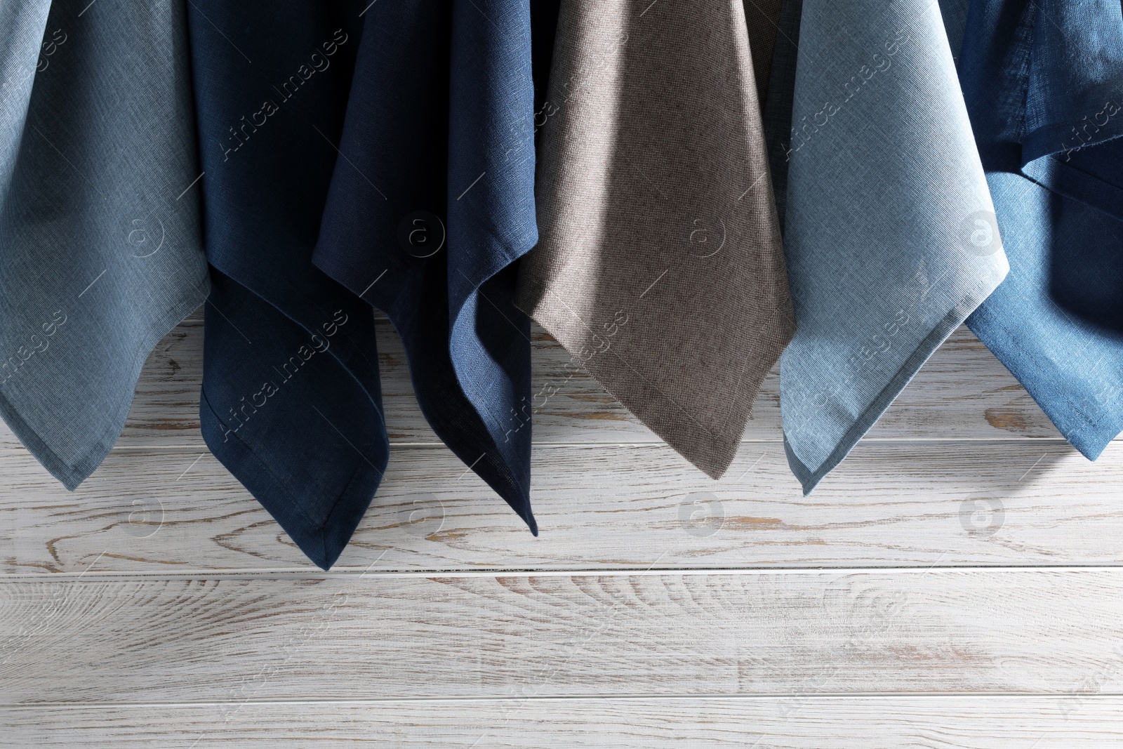 Photo of Different kitchen napkins hanging on white wooden wall