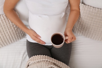 Pregnant woman drinking tea at home, closeup