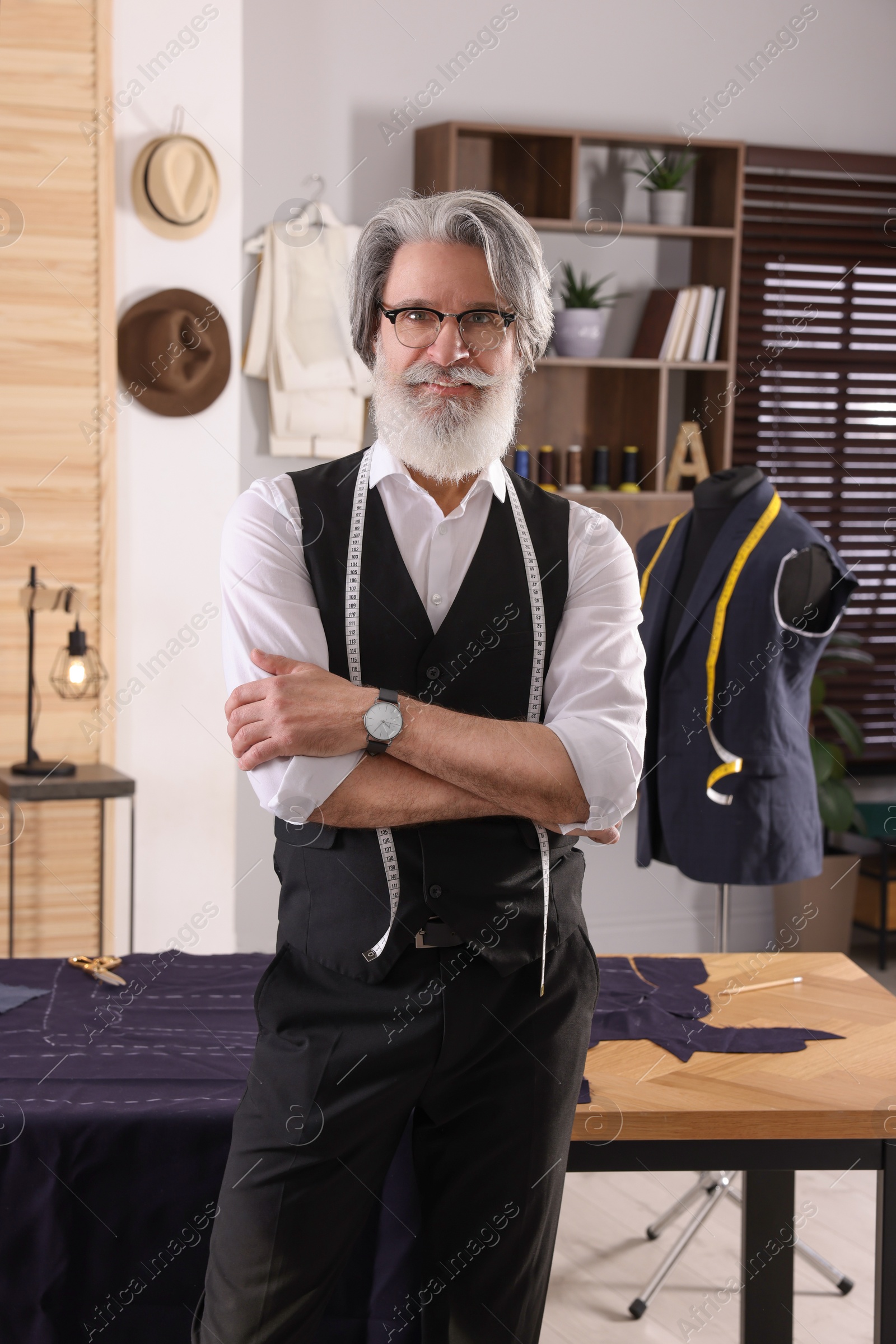 Photo of Professional tailor with measuring tape in workshop