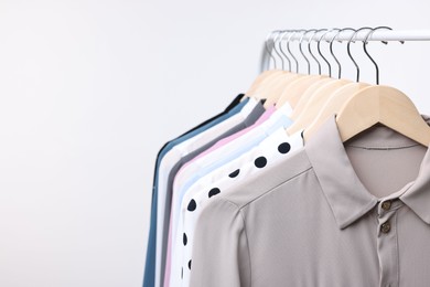 Photo of Dry-cleaning service. Many different clothes hanging on rack against white background, space for text