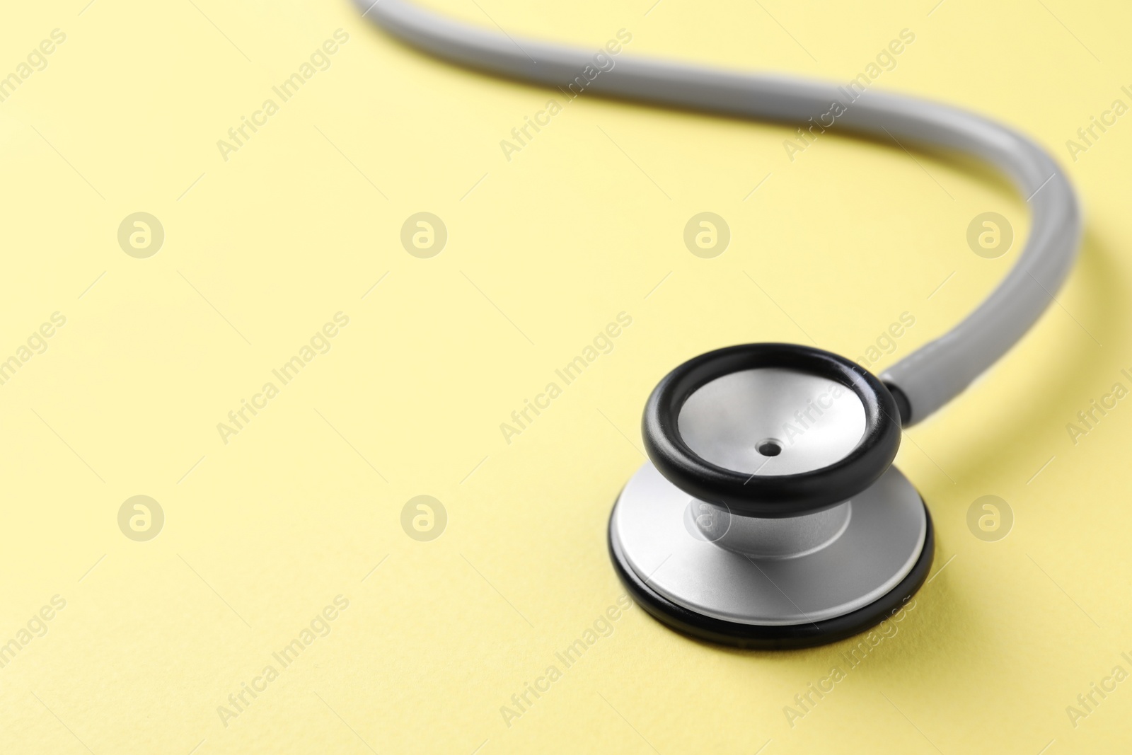 Photo of Stethoscope on yellow background, closeup. Space for text