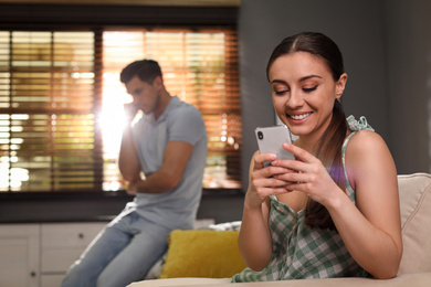 Photo of Woman preferring smartphone over spending time with her boyfriend at home. Jealousy in relationship