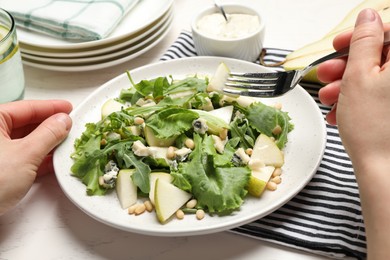 Woman with tasty pear salad at white table, closeup